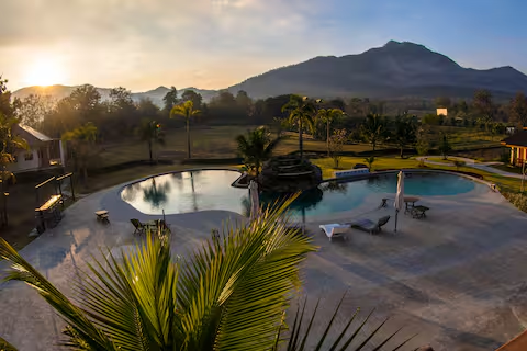 Golden-hour view of the resort pool with mountains at sunset