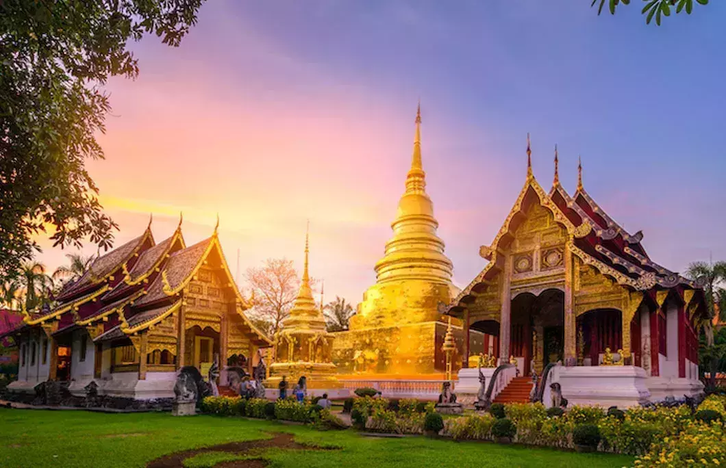 Wat Phra Singh temple in Chiang Mai with a golden chedi and ornate Lanna buildings at sunset
