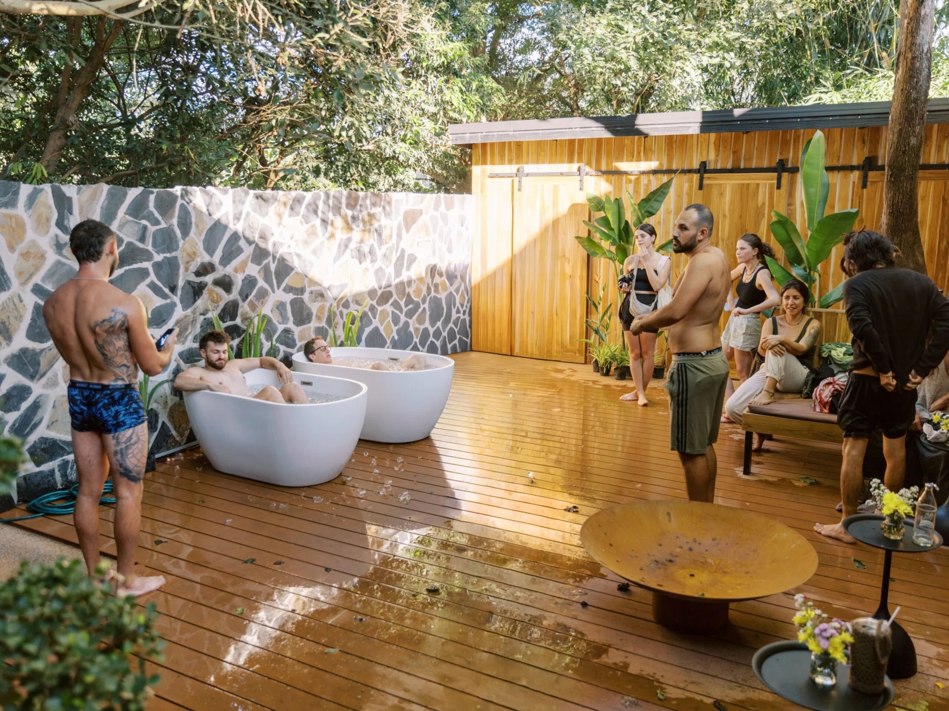 Outdoor cold plunge ice baths on a timber deck with people gathered at The Ark