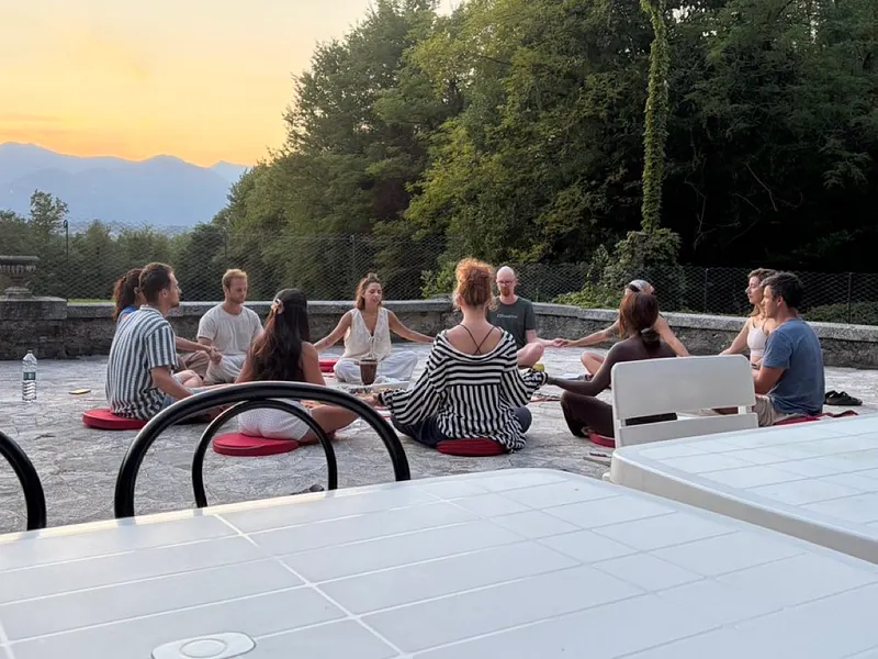 Group meditation circle at sunset on a mountain terrace