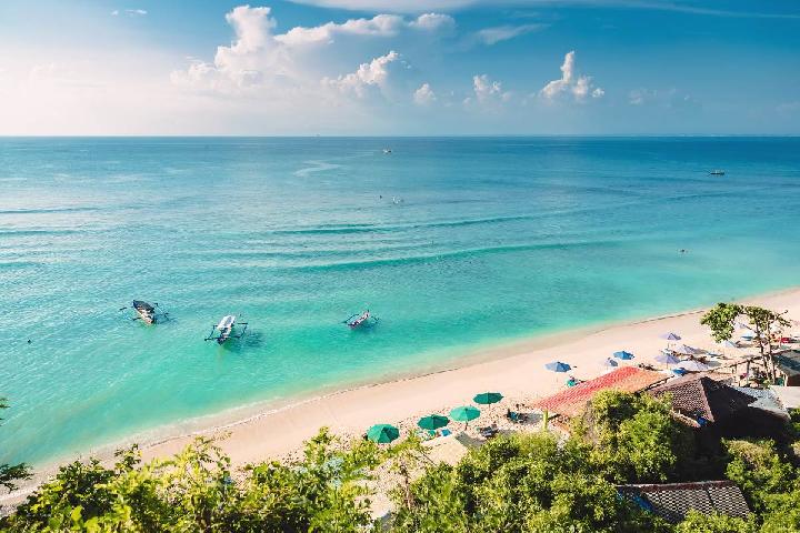Aerial view of a turquoise Bali beach with traditional outrigger boats and white sand