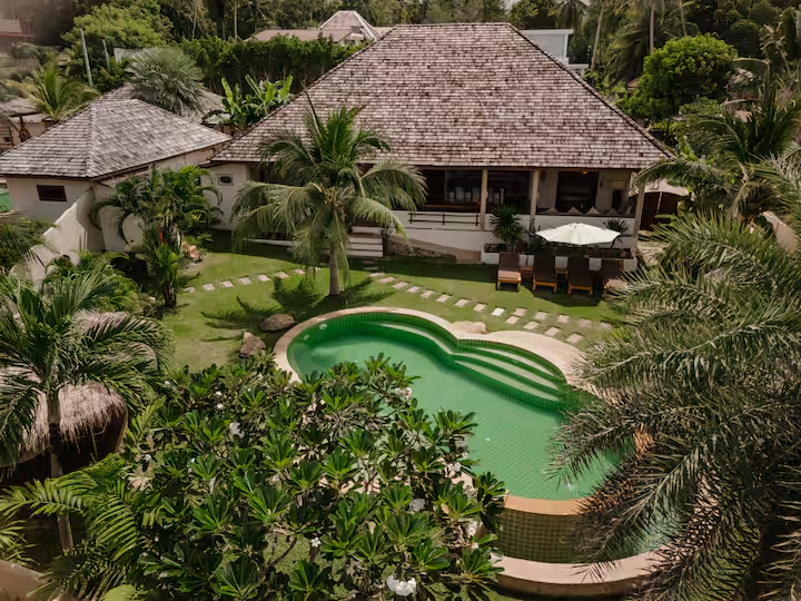 Aerial view of the villa with a green pool and lush garden