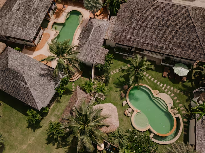 Overhead view of both villas and their two swimming pools surrounded by palms