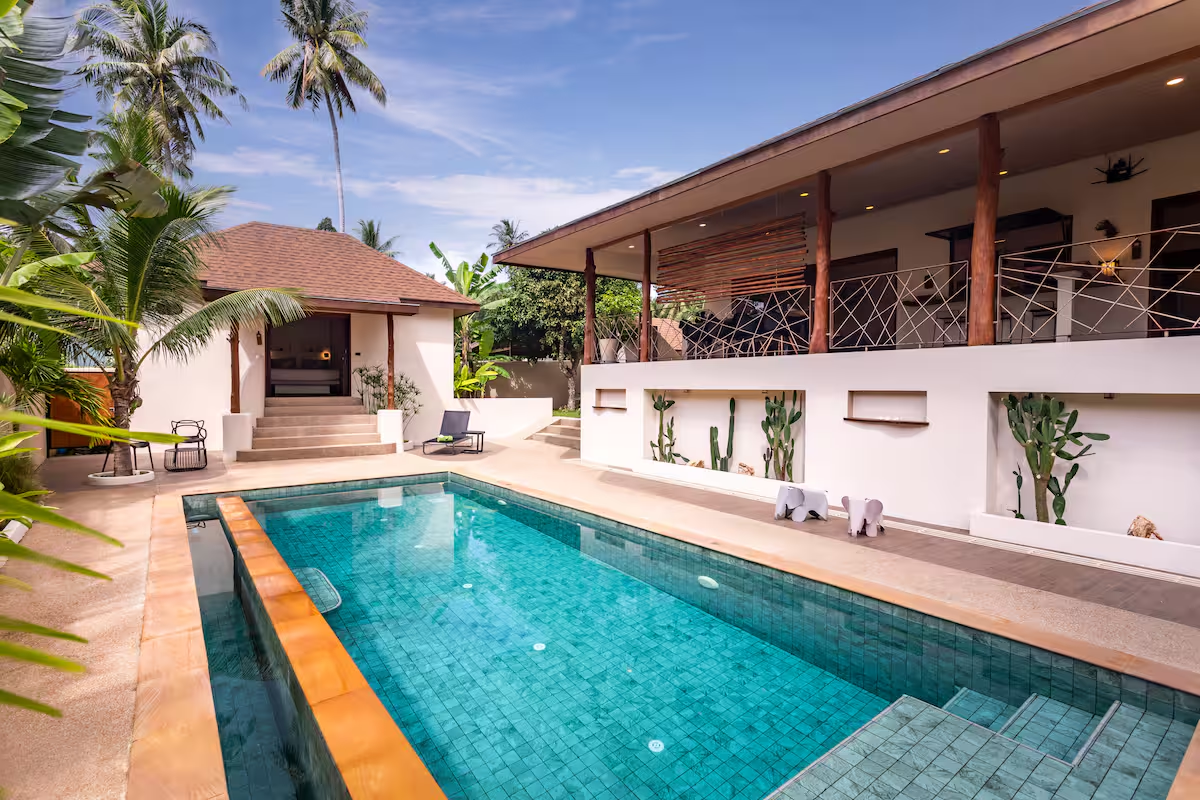 Turquoise pool beside the villa's covered terrace with timber columns and cactus planters
