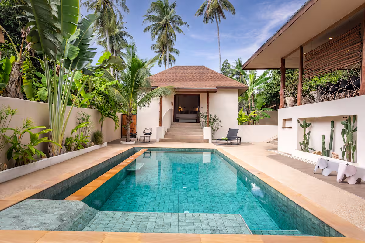 Garden pool with a private suite entrance framed by palms and tropical plants